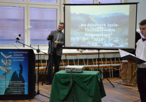 Prof. Jacek Malinowski w obecności uczniów prowadzących Konkurs dostosowuje mikrofon dla uczestników.